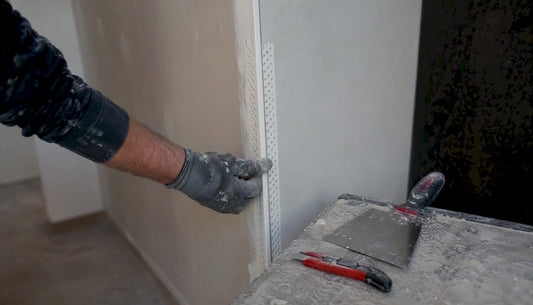 Hand fitting galvanized metal drywall corner bead on wall corner