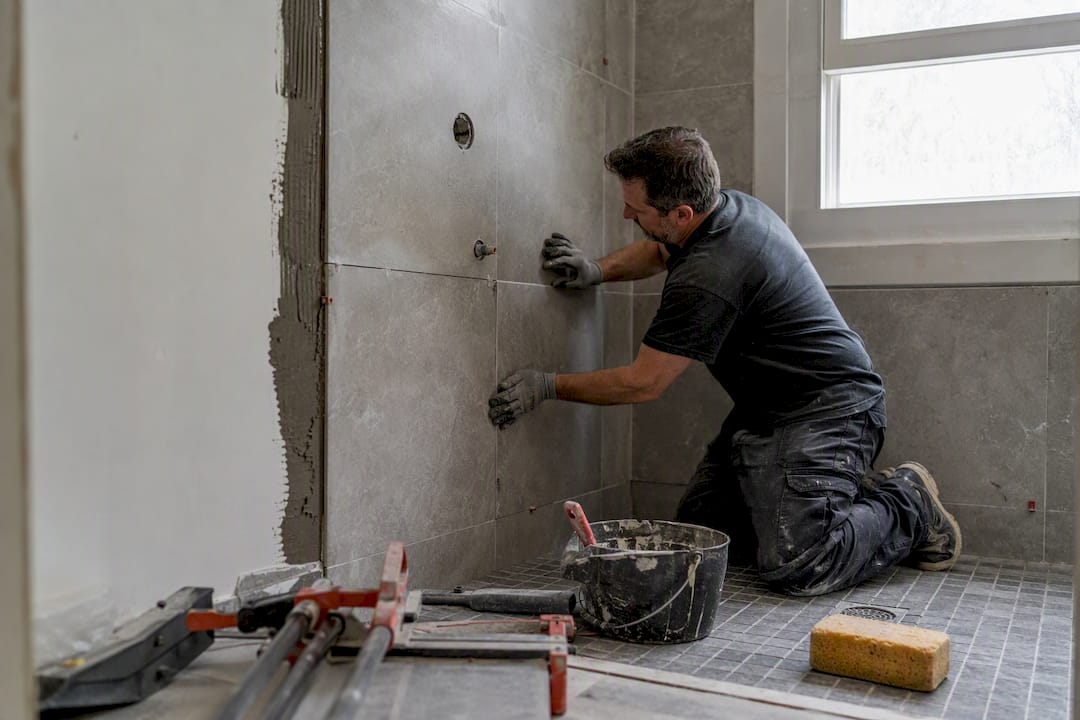 Worker applying waterproofing membrane in shower alcove
